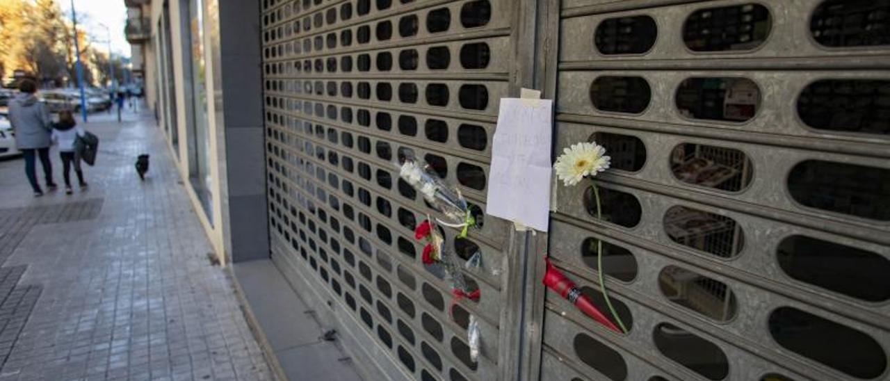 Flores y mensajes de duelo en la persiana de la ferretería.  | PERALES IBORRA