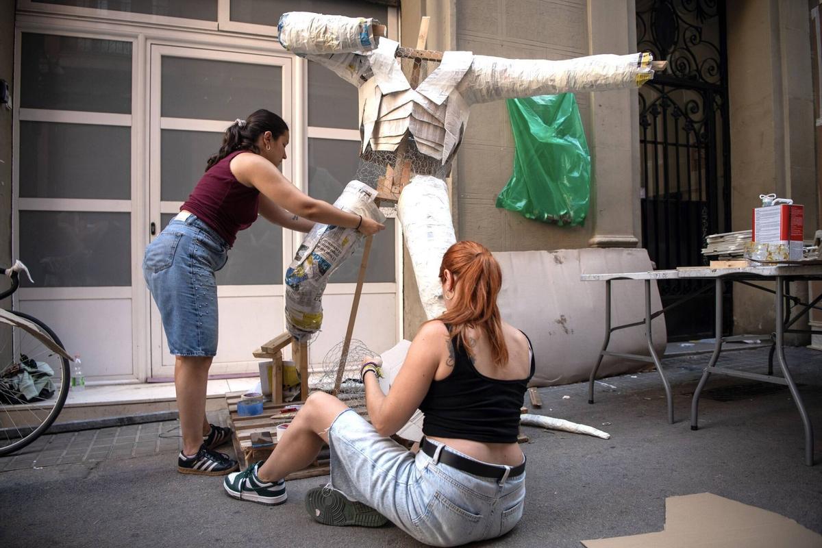 Dos vecinas de la calle Congrés construyendo una figura humana, durante la creación de ‘guarnits’ para las fiestas mayores de Gràcia. Este año, 5 calles del barrio se han unido bajo la temática de ‘El Señor de los Anillos’. Barcelona, 4 de agosto de 2026. Foto: Belén González / EP