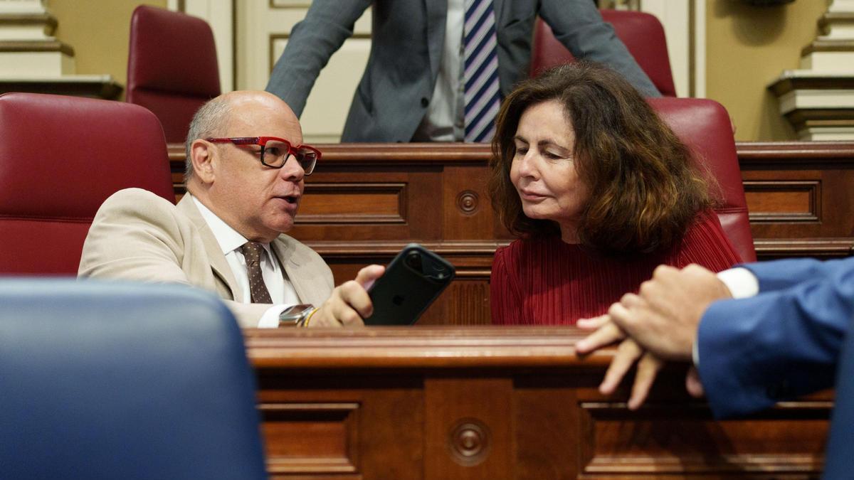 José Miguel Barragán y Matilde Asián observan la pantalla de un móvil durante el pleno del Parlamento canario.