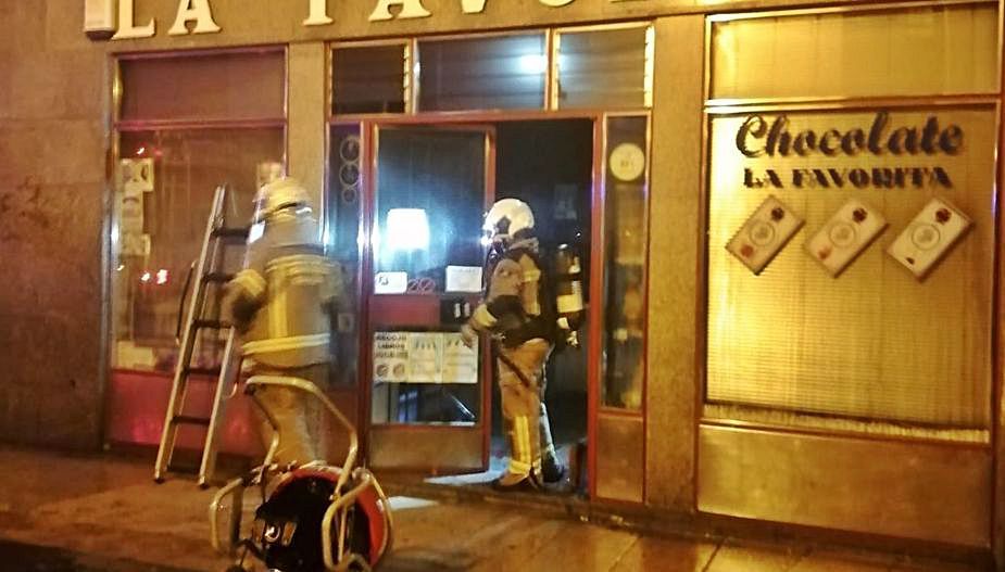 Efectivos de bomberos sofocan las llamas provocadas por un cortocircuito en una tienda en la madrugada de ayer en Oviedo. | LNE