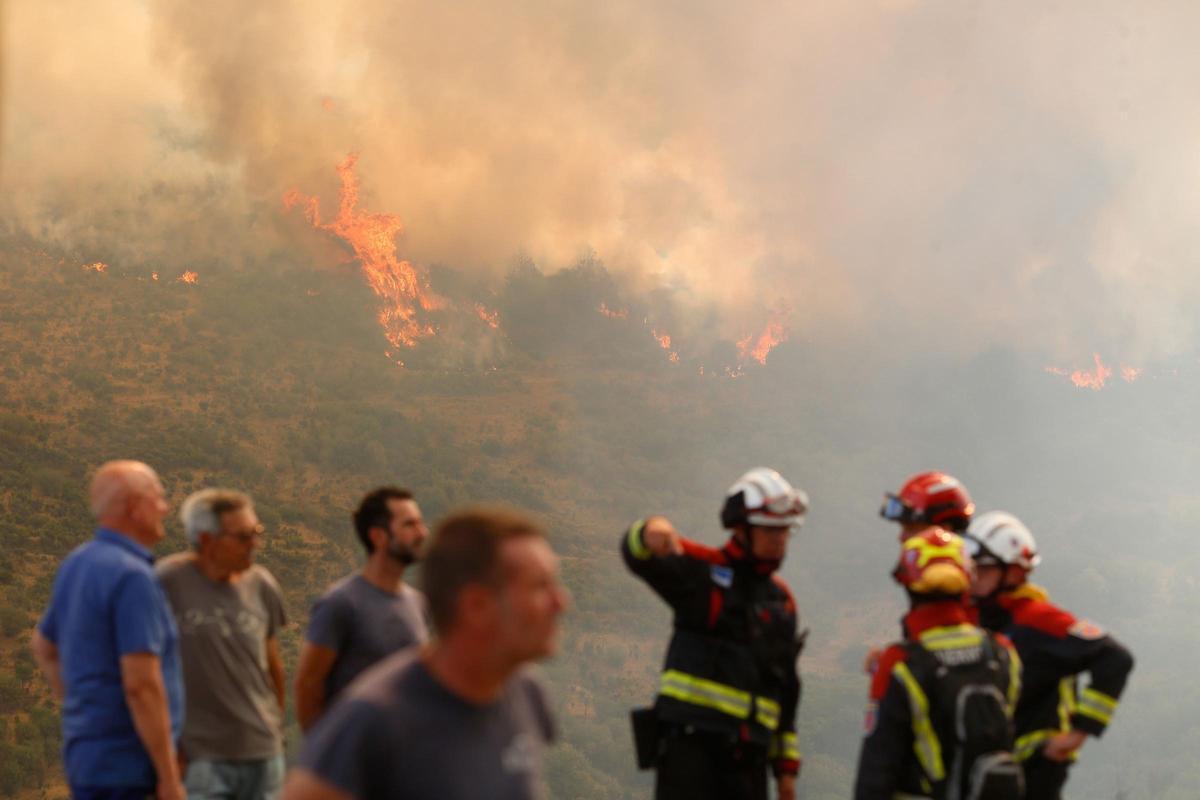 Archivo - Varias personas observan uno de los incendios forestales en la provincia de León el pasado mes de agosto.