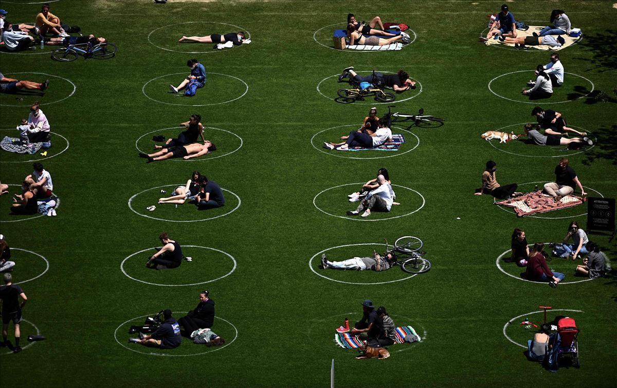 Personas practicando el distanciamiento social en círculos blancos en Domino Park, durante la pandemia de Covid-19 el 17 de mayo de 2020 en el distrito de Brooklyn de la ciudad de Nueva York