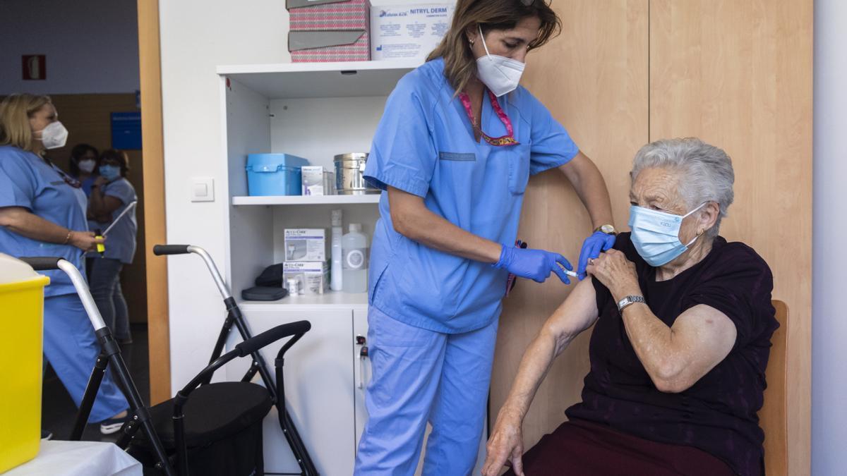 Una mujer de más de 80 años recibe la doble vacuna covid-gripe en su centro de salud