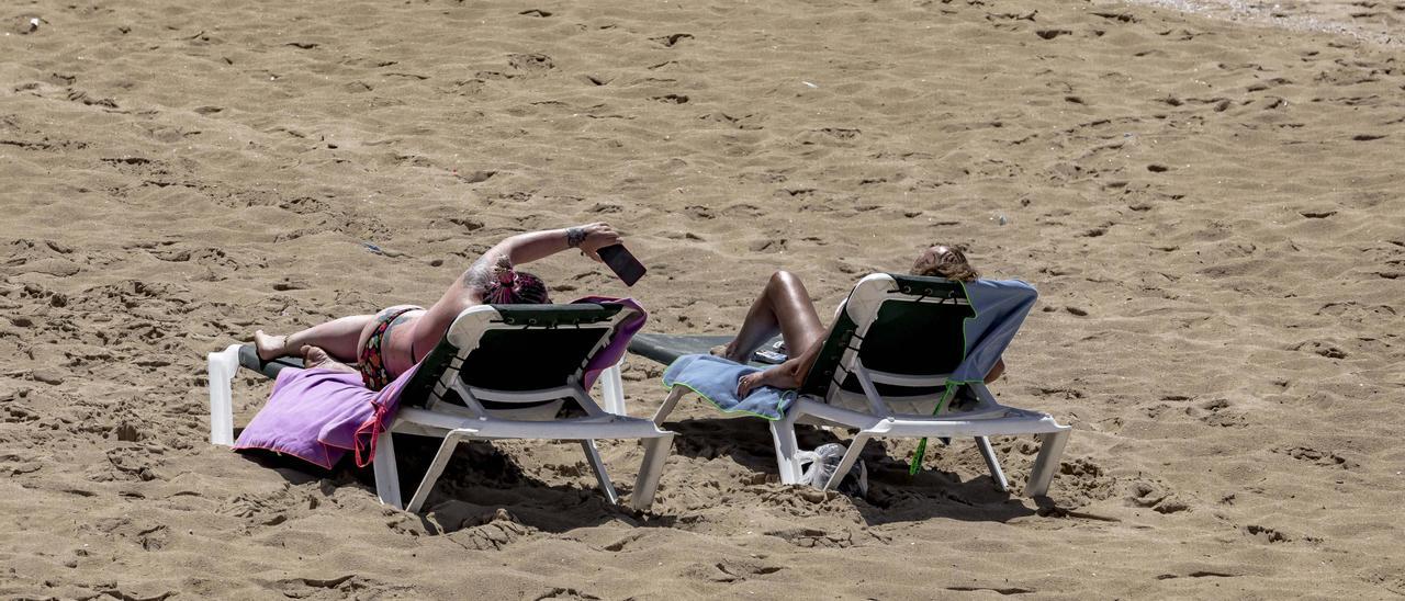 Dos personas tomas el sol en la playa de Can Pere Antoni, en Palma