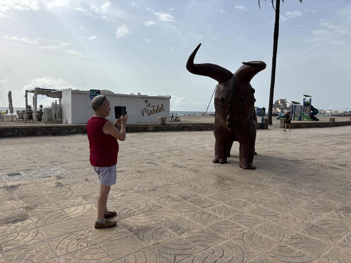 Hombre fotografiando la escultura 'El toro de dos cabezas' de Ripollés, situada en la avenida Papa Luna