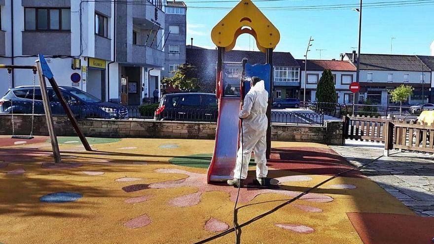 Un operario realiza labores de desinfección en un parque infantil en Teixeiro (Curtis).