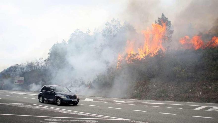 Un vehículo circula por la EP-7001, a pocos metros del incendio. // Bernabé/Ana Agra