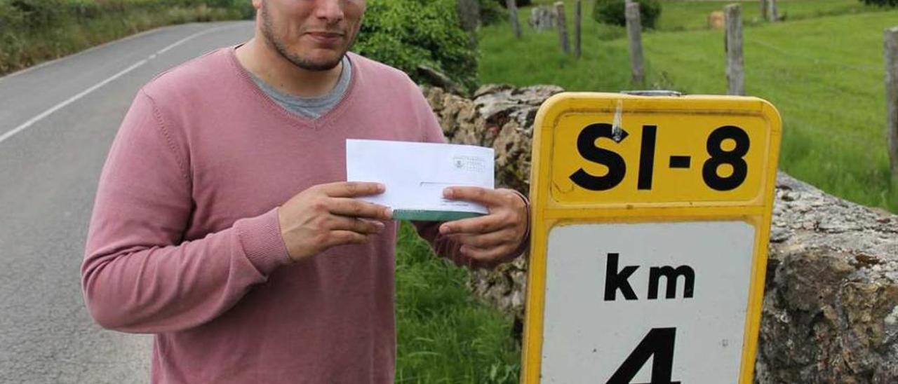 Efrén Suárez sostiene una carta en Valdesoto junto a una señal que indica la localización en Siero.