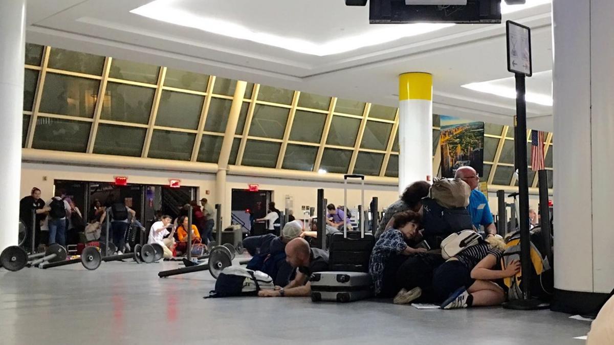 Pasajeros del aeropuerto JFK de Nueva York se protegen mientras la policía busca a un presunto tirador, la pasada madrugada.