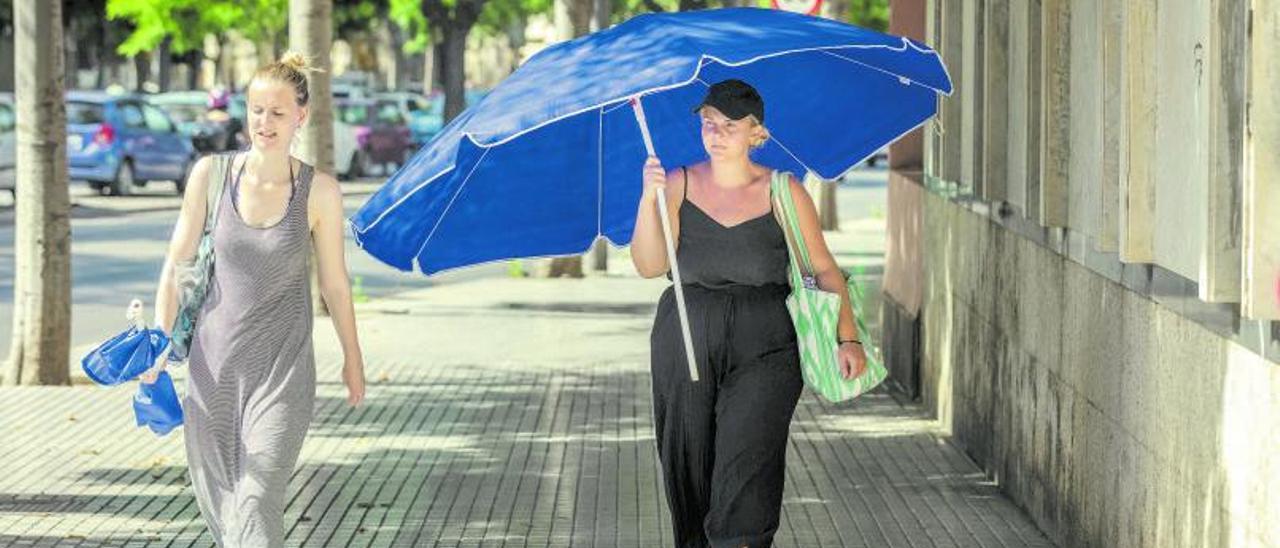 Dos turistas  acaloradas en la isla, paseando con la sombrilla para protegerse. | B. RAMON
