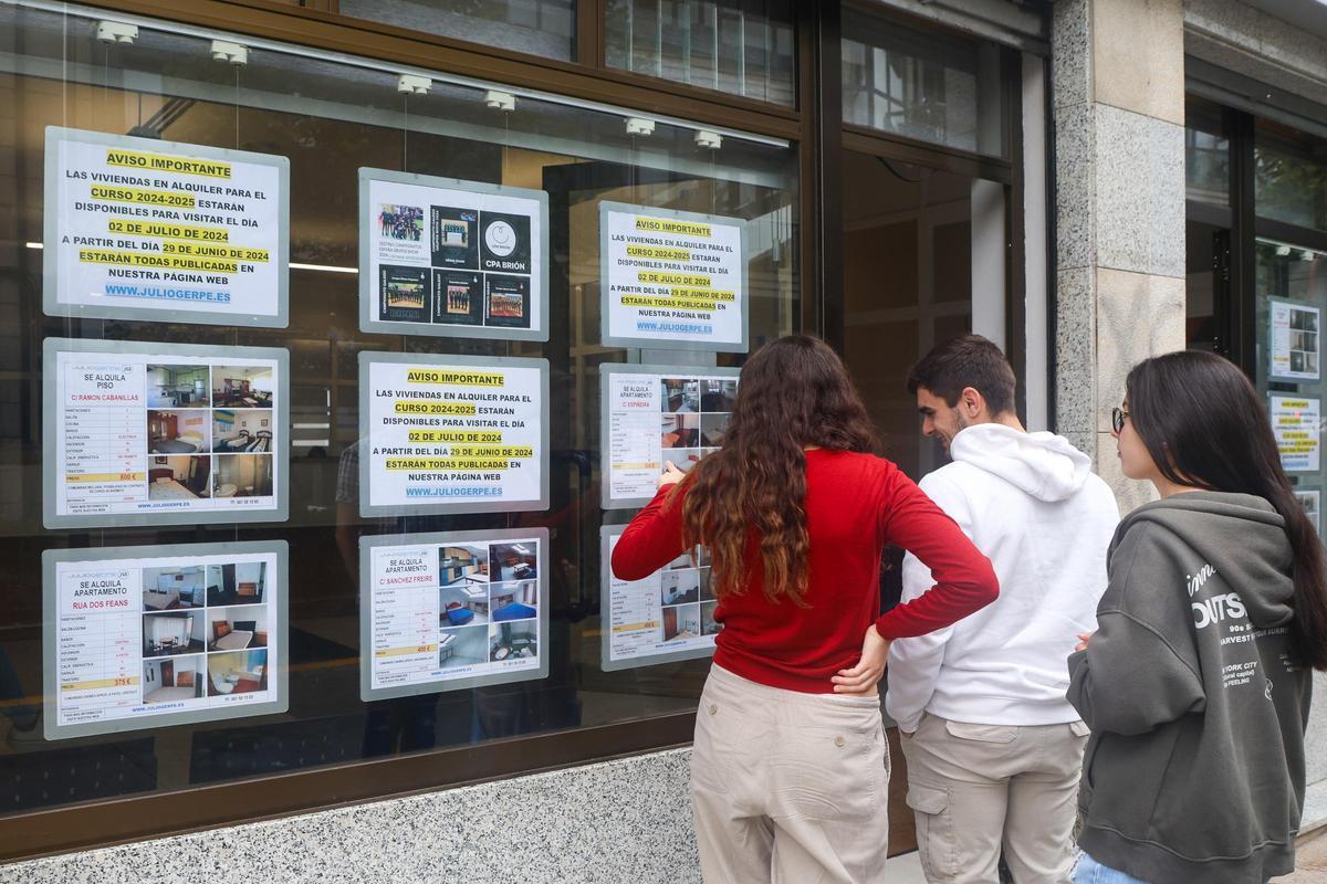 Unos estudiantes miran anuncios de pisos en alquiler en una inmobiliaria.
