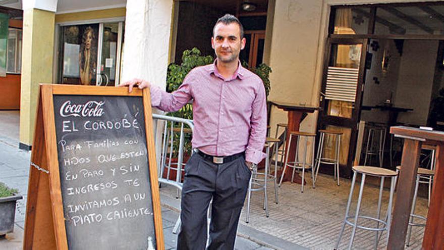 Emilio José Aguilar, en el exterior de su bar, junto al letrero que anuncia la iniciativa.