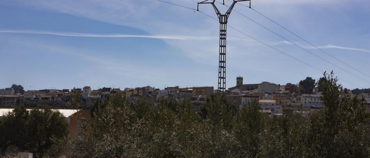 Una torre del tendido eléctrico aéreo y detrás el casco urbano de la Font de la Figuera. | PERALES IBORRA