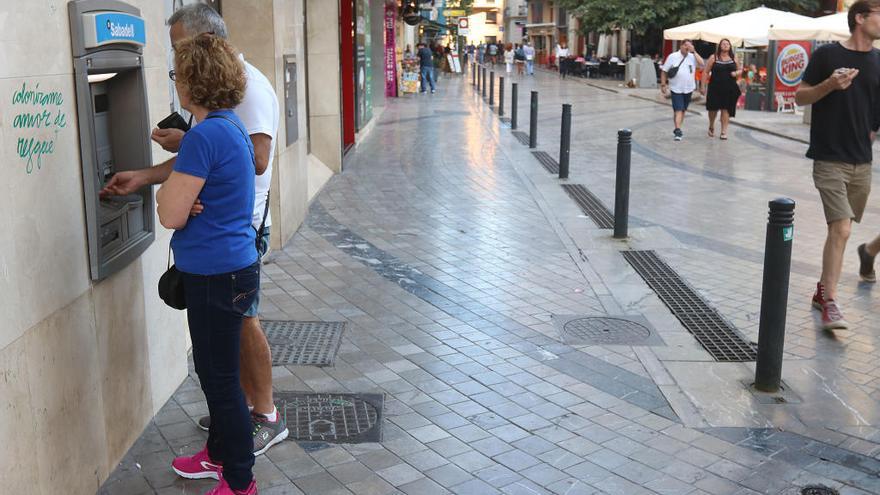 Clientes de una entidad financiera sacan dinero de un cajero.