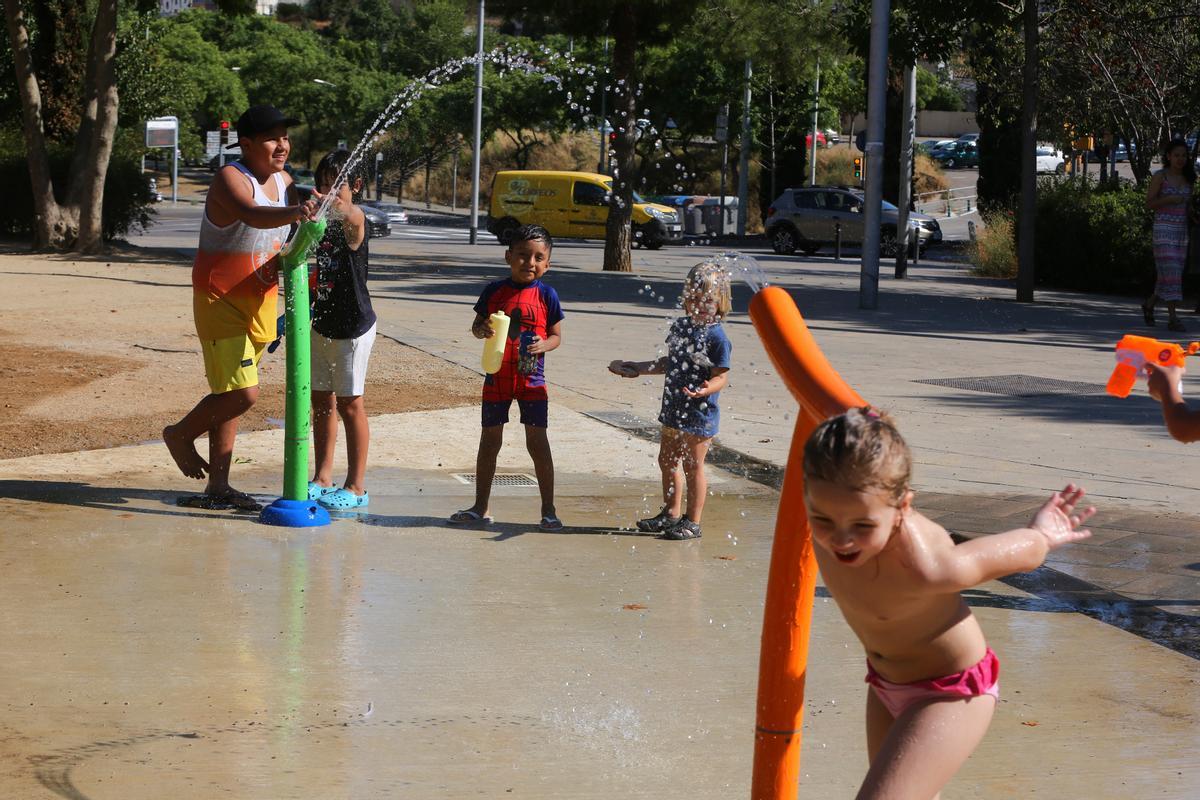 Niños refrescándose esta tarde en Barcelona del calor
