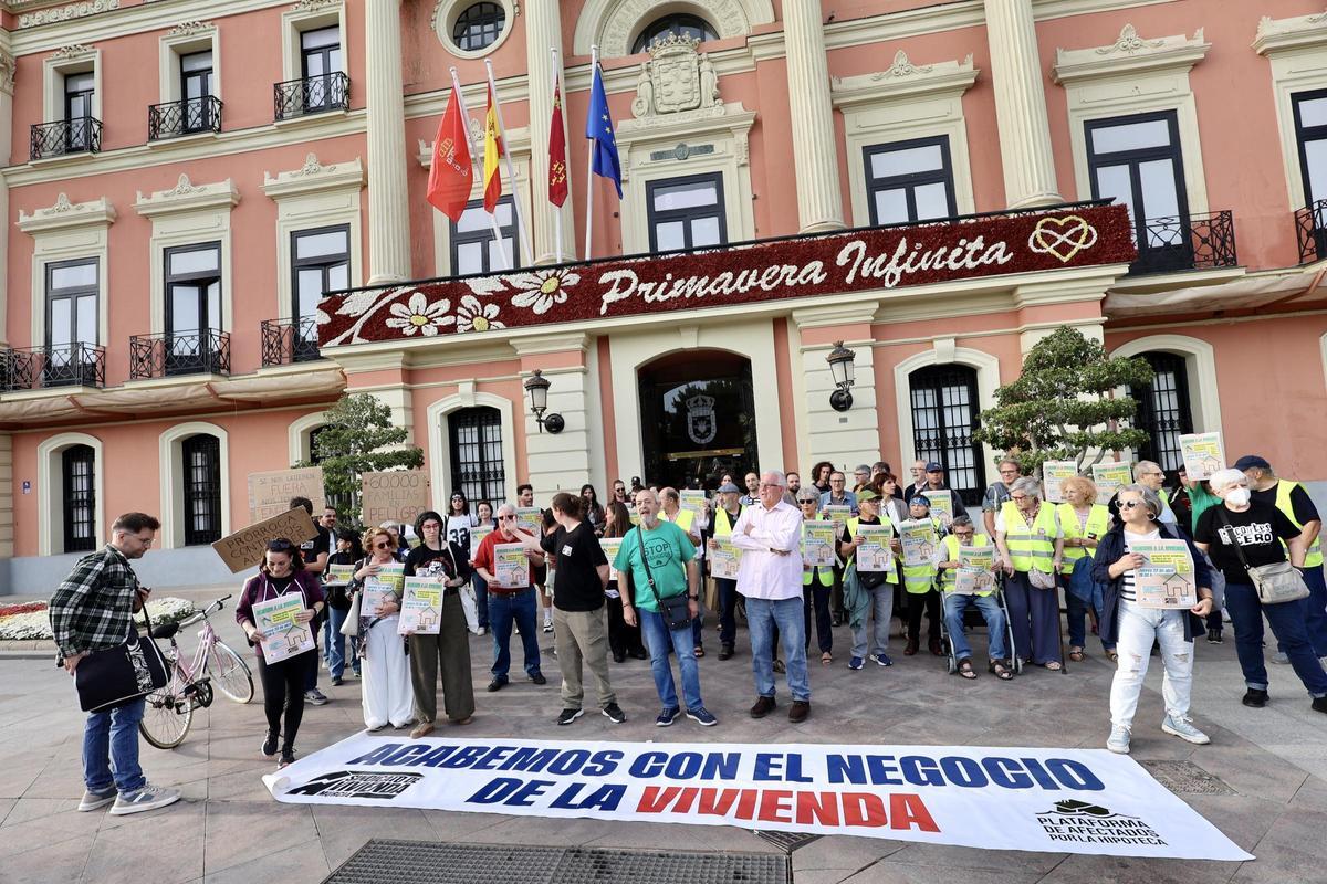 Manifestantes, a las puertas del Ayuntamiento de Murcia, junto a una pancarta con el lema 'Acabemos con el negocio de la vivienda'