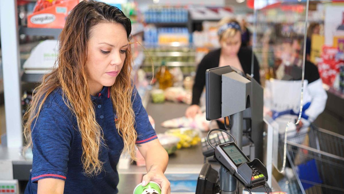 Una cajera pasa una compra en el supermercado.