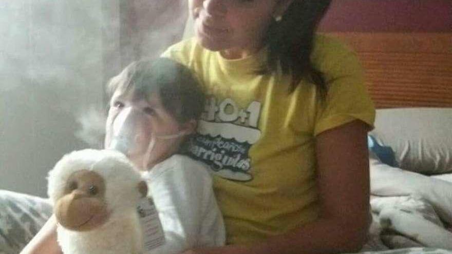 Cristina Vega, con su hijo Pablo, mientras usa la mascarilla del tratamiento contra la fibrosis.