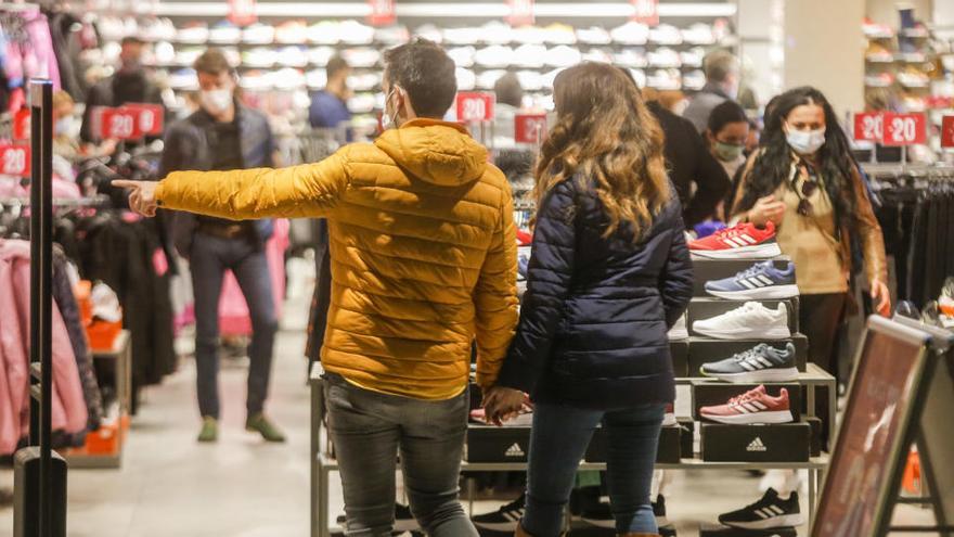 Varias personas realizan compras en una tienda en España.