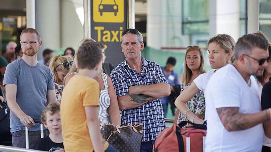 Turistas esperan en la zona del aeropuerto destinada a taxis.