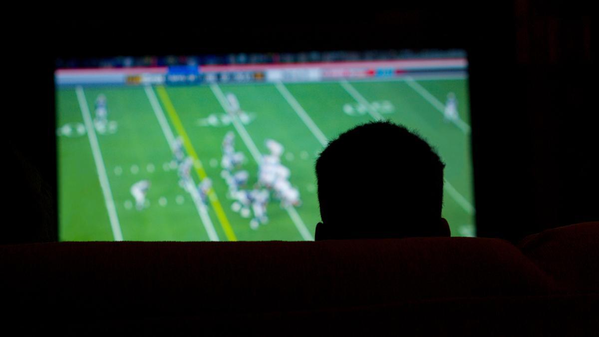 Un hombre ve en la televisión un partido de la NFL.