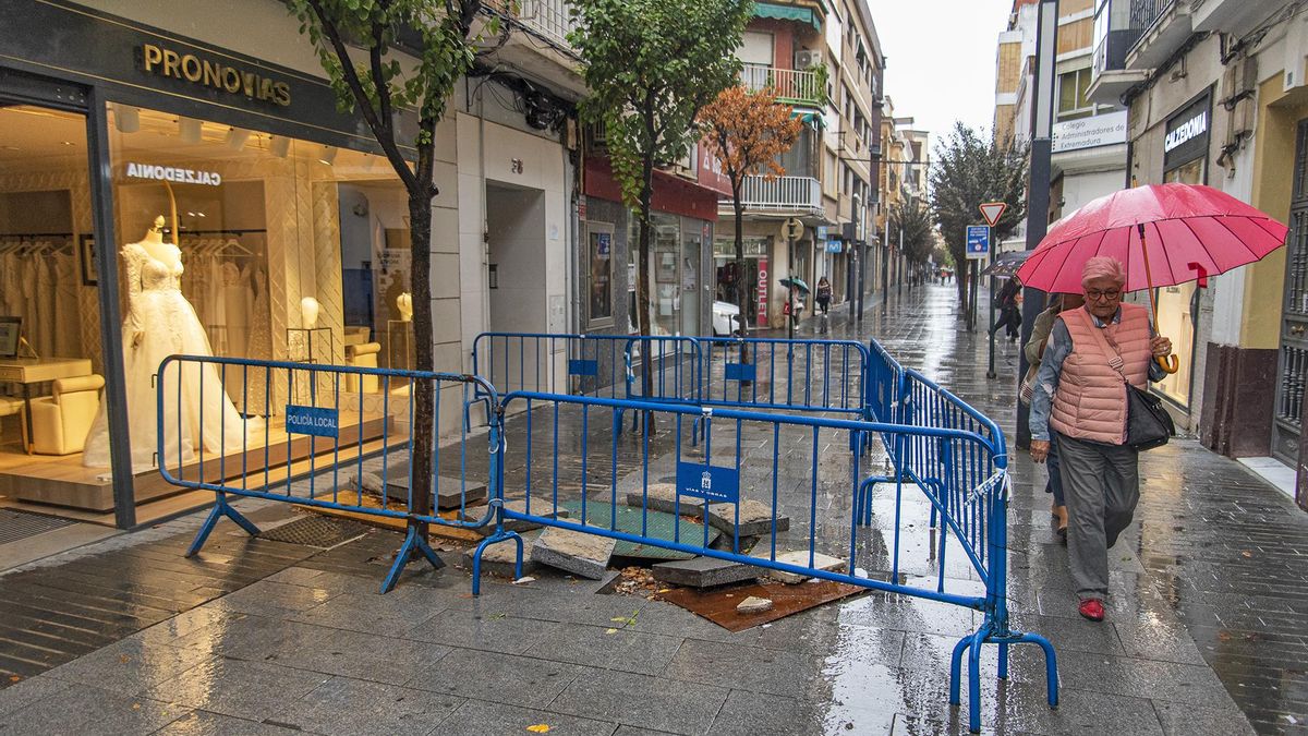 Una mujer pasa por el estrecho espacio que permite el socavón de la calle Menacho.