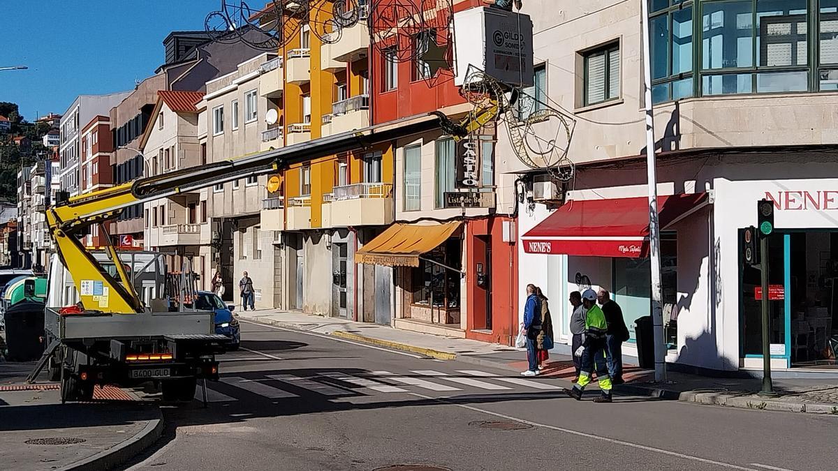 Operarios de Gildo Sonido colocan los arcos a lo largo de la calle Pazos Fontenla en Bueu.