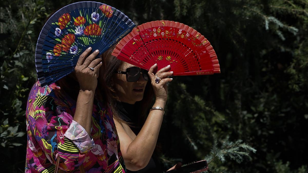 Dos mujeres se protegen del calor en el parque del Retiro de Madrid.