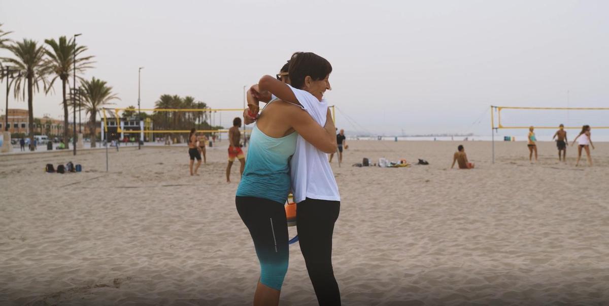 Amparo Folch entre a una alumna en la playa