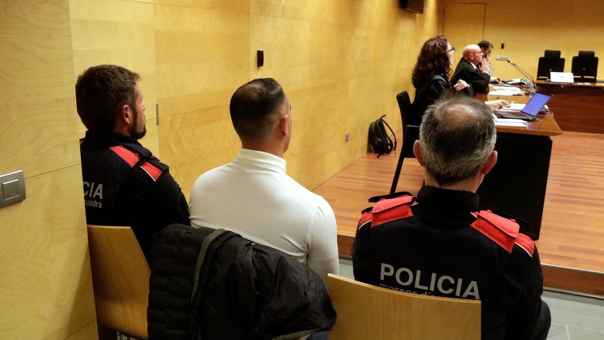 D'esquenes i custodiat pels Mossos, l'acusat del crim de Calonge. Foto del judici a l'Audiència de Girona