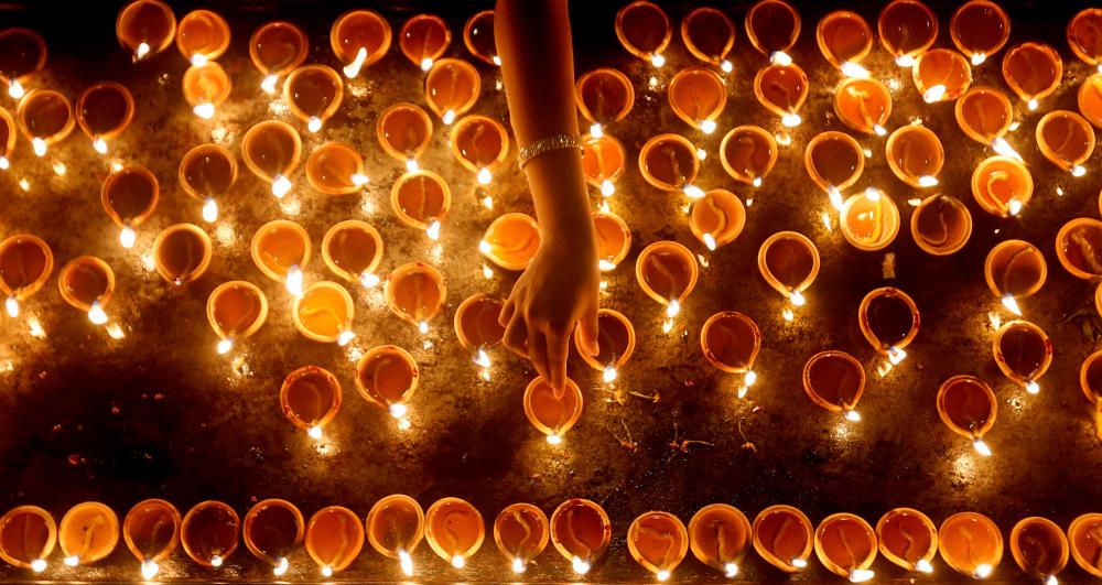 A devotee lights oil lamps at a religious ...