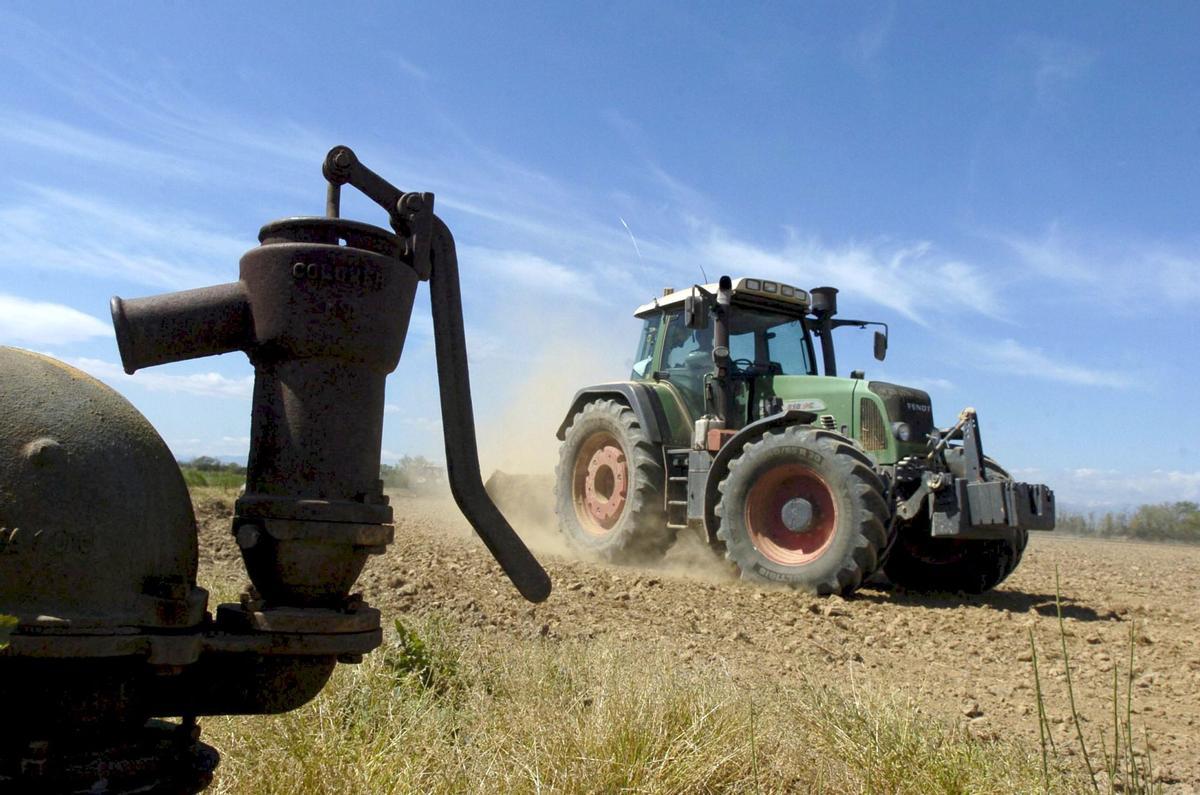 Un tractor trabaja junto a una bomba de agua.