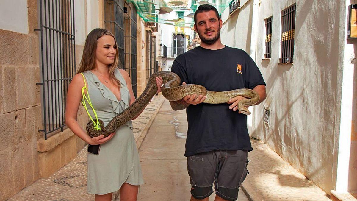 Mónica y César posan con su serpiente pitón en la calle donde el reptil sorprendió a los vecinos. |