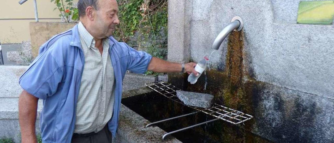 José Álvarez cogiendo agua, ayer, en la fuente de El Reguerón.