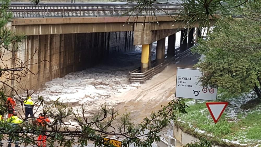 Pluja i calamarsa acumulada a la carretera en el punt en què passa sota la via del tren a Celrà