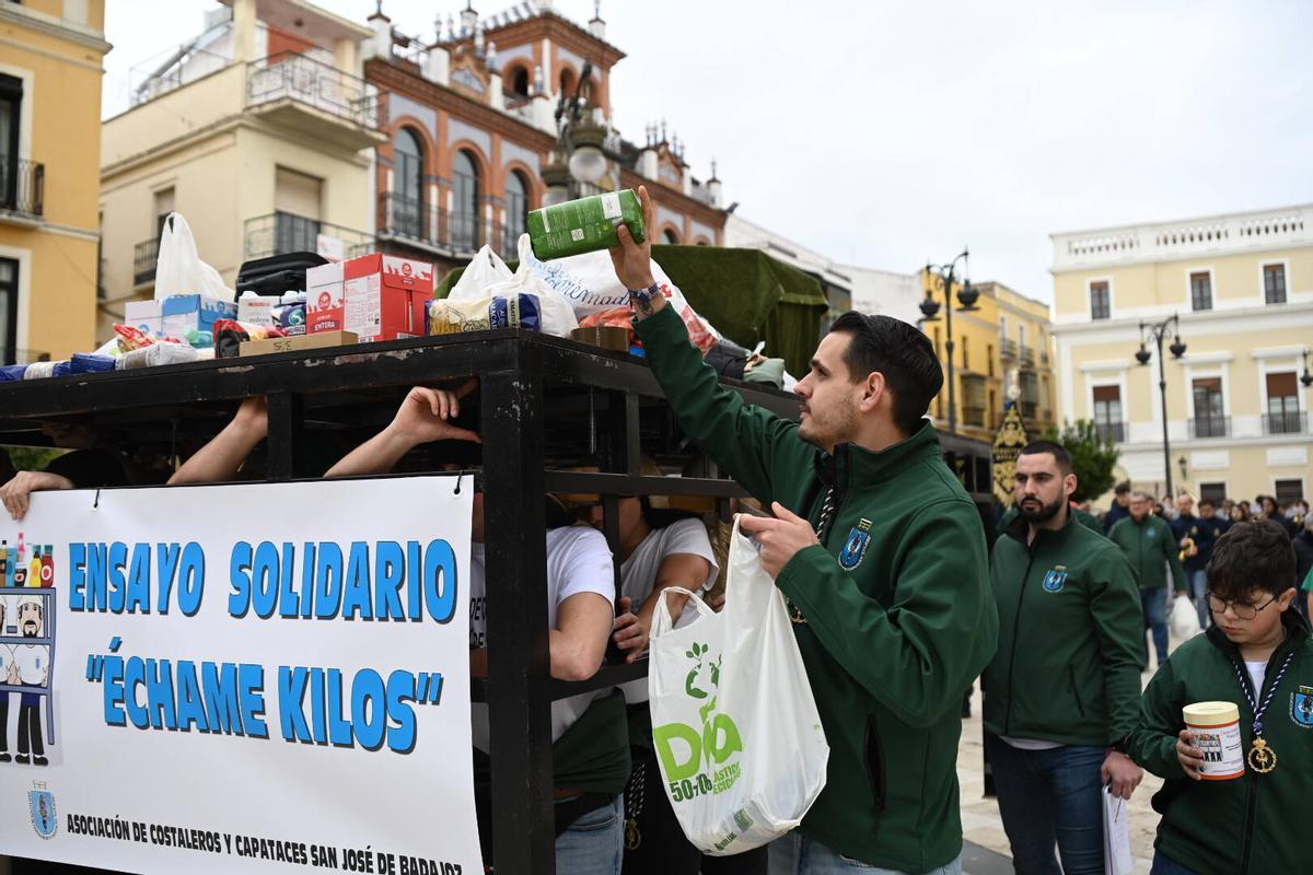 Un costalero deposita alimentos donados durante el paso del Ensayo Solidario por la plaza de España.