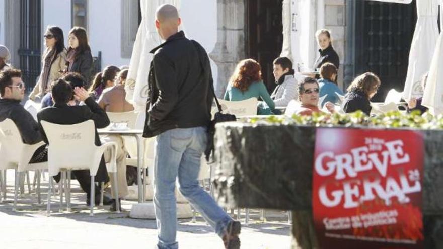 Terrazas llenas ayer en la plaza principal de Viana con un cartel de la huelga en primer plano. / j. lores