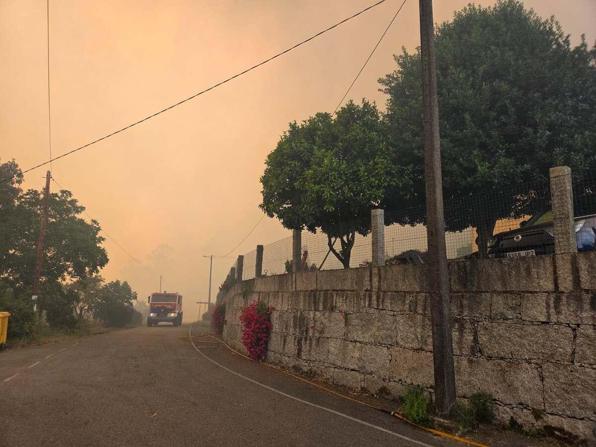 Una motobomba avanza por uno de los núcleos padroneses situados cerca de las llamas