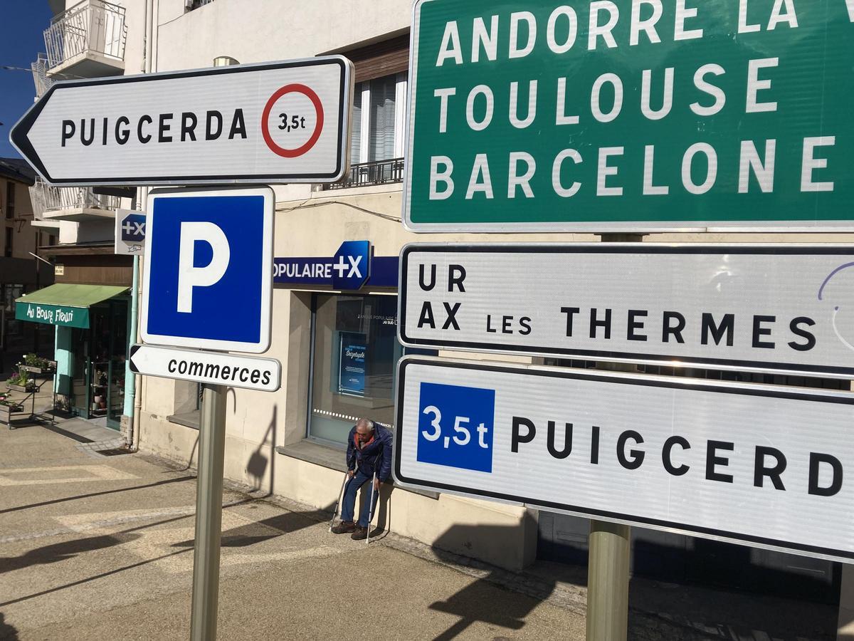 Un veí de la Guingueta d'Hix entre els rètols de direccions entre Puigcerdà i Tolosa