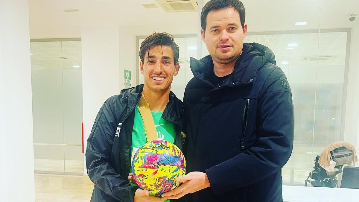 Pere Milla posa junto a su representante con el balón del triplete