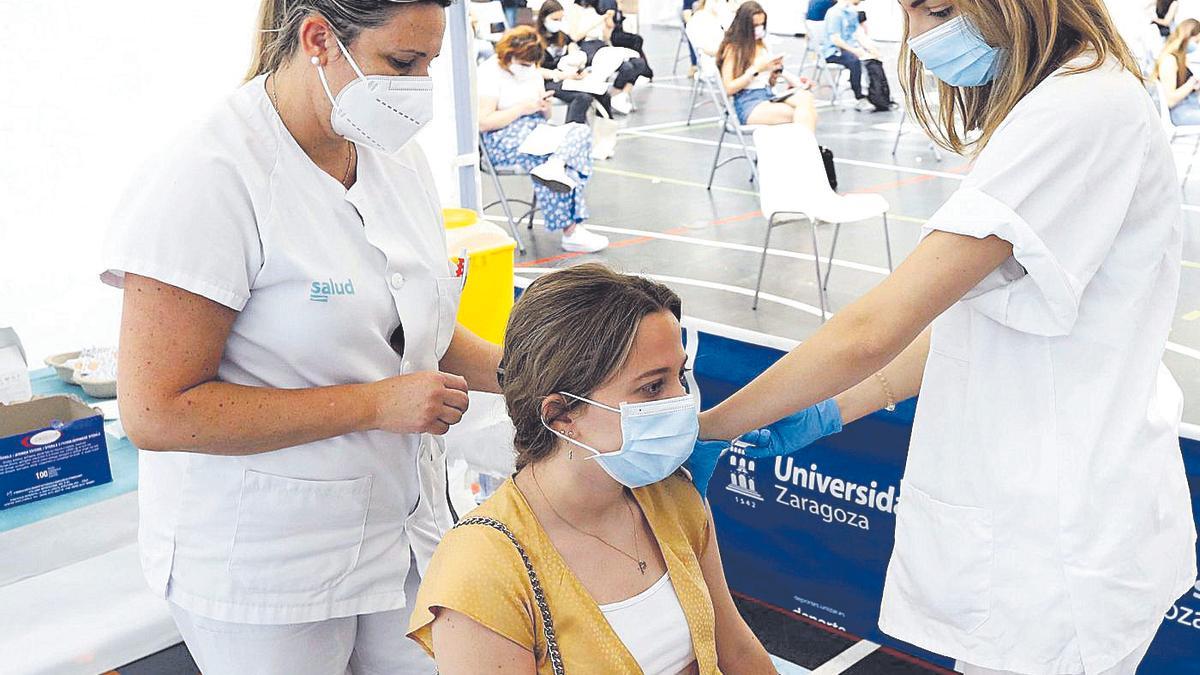 Dos enfermeras vacunan a una joven contra el covid en el pabellón de la Universidad de Zaragoza.