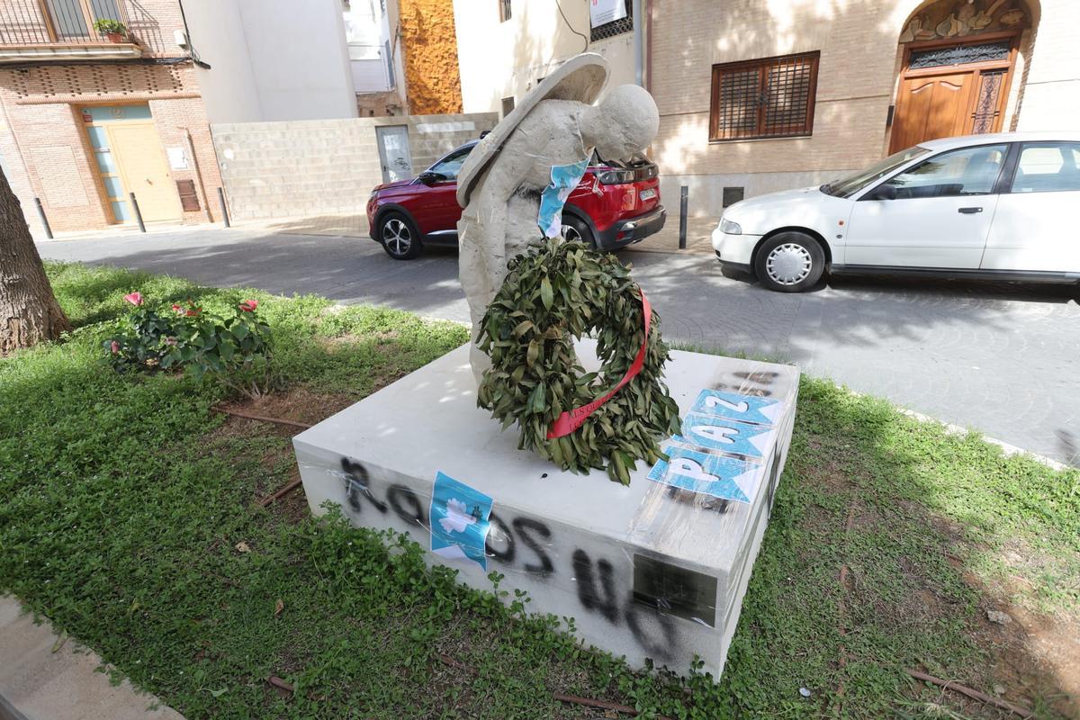 La escultura vandalizada con los carteles de la paz.