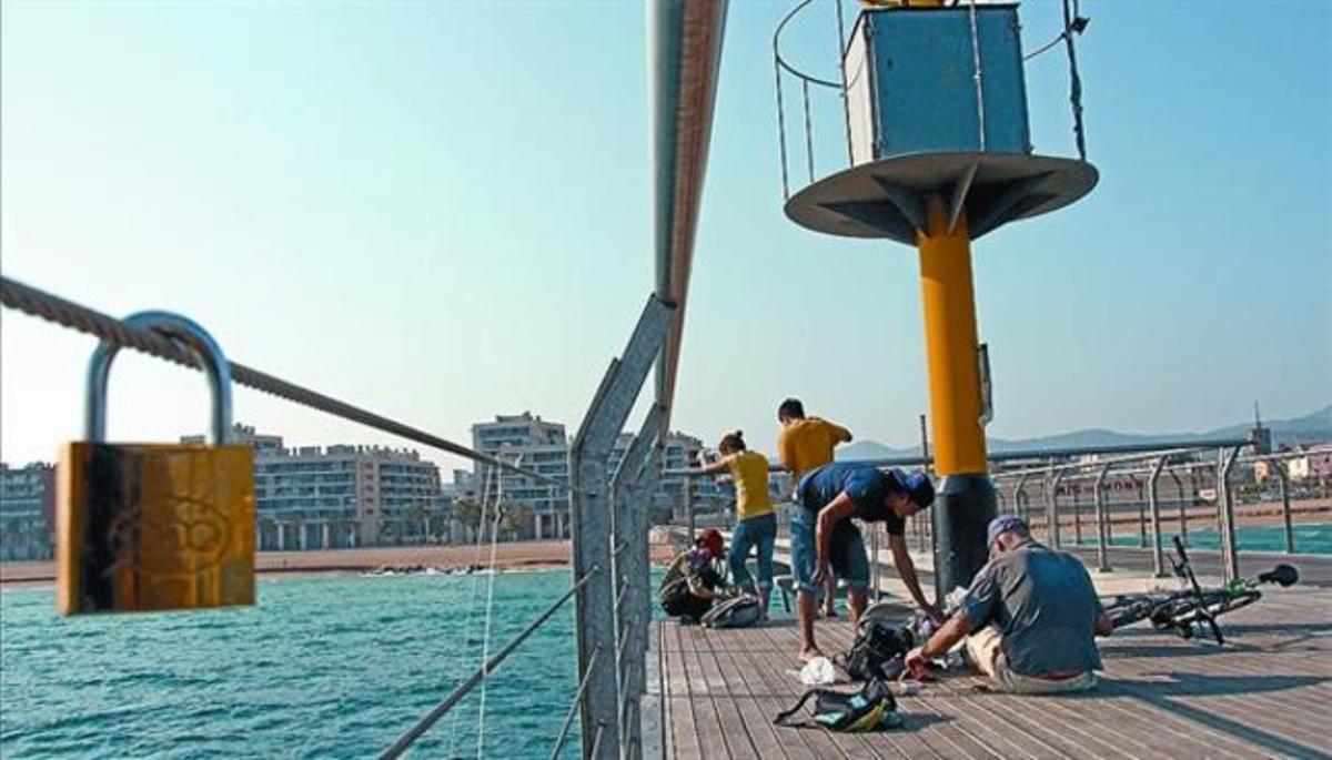 Un cadenat penjat al Pont de Petroli, de Badalona, a prop d’uns pescadors.