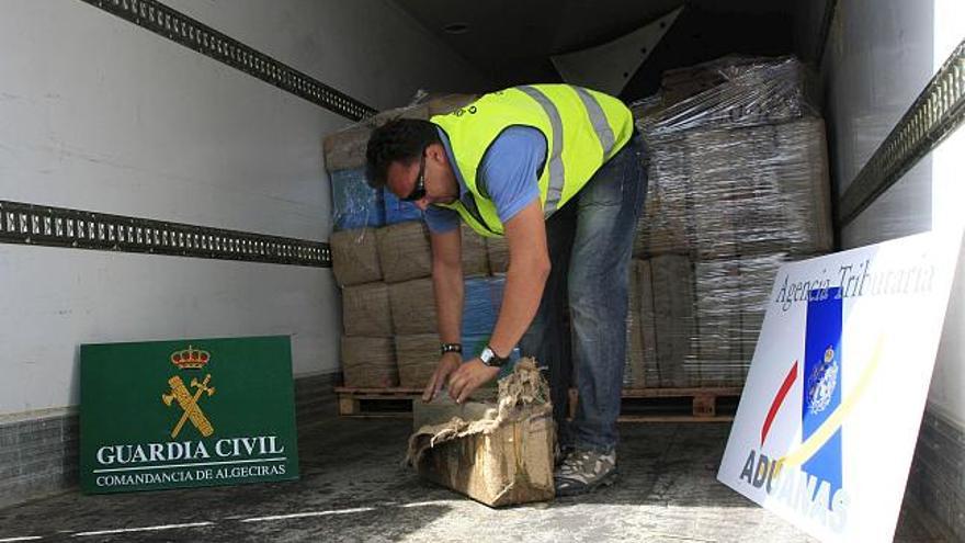 Un agente de la Guardia Civil inspecciona uno de los fardos de droga, 19,4 toneladas de polen y resina de hachís, que han incautado hoy en un semirremolque en el puerto de Algeciras (Cádiz) procedente de Tánger (Marruecos), que declaraba transportar sandías. En un comunicado, el instituto armado ha informado de que la operación se inició tras averiguar la supuesta duplicidad de matrículas en dos transportes, pertenecientes a una empresa que realizaba viajes desde Marruecos hasta Perpignan (Francia), con tránsito en el puerto de Algeciras, y sospechar que podrían estar dedicándose al narcotráfico.