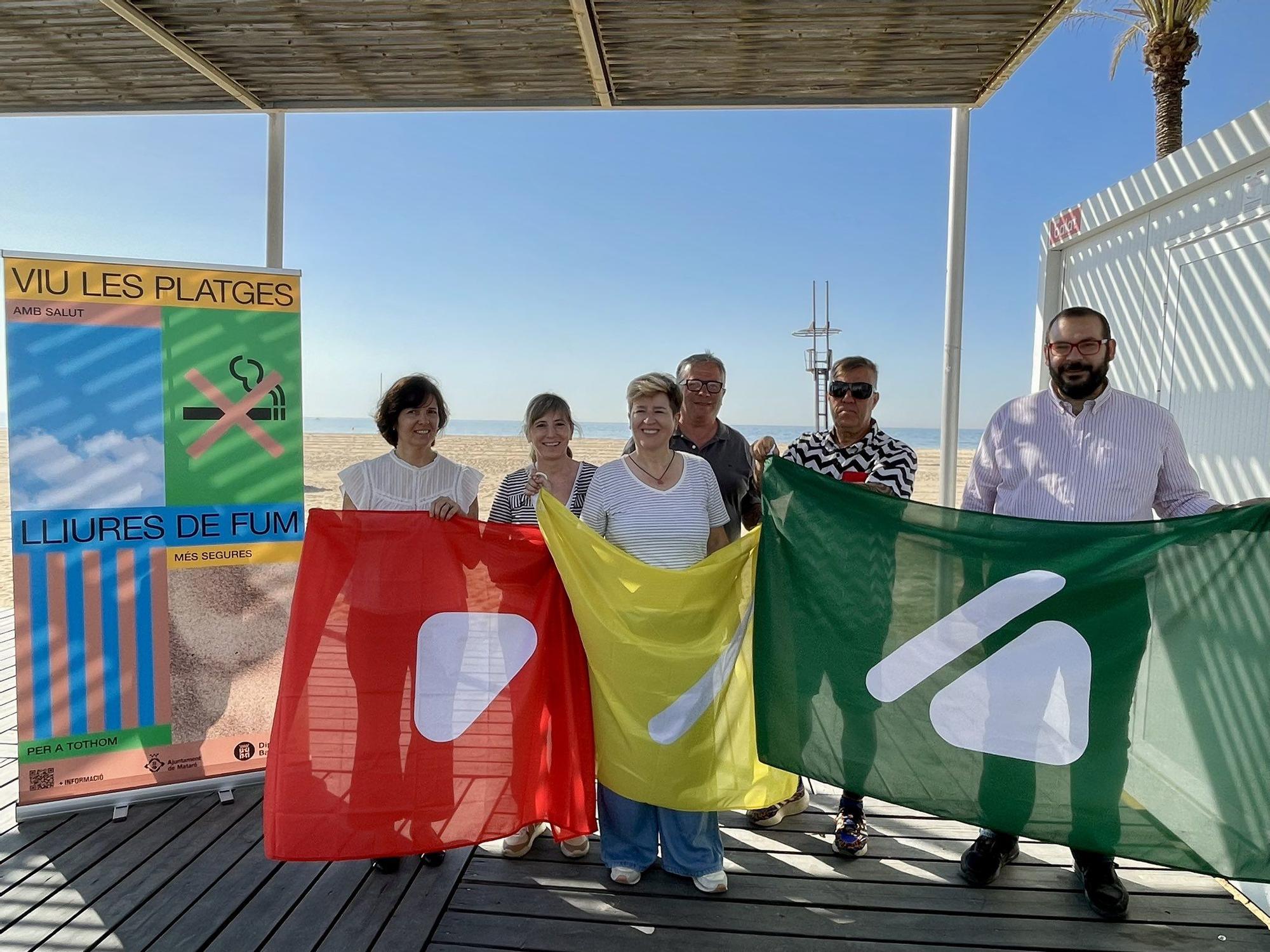 El alcalde de Mataró, David Bote, y más representantes municipales, lucen las banderas de playa adaptadas a daltónicos durante la presentación de la temporada de baño, este jueves 28 de mayo