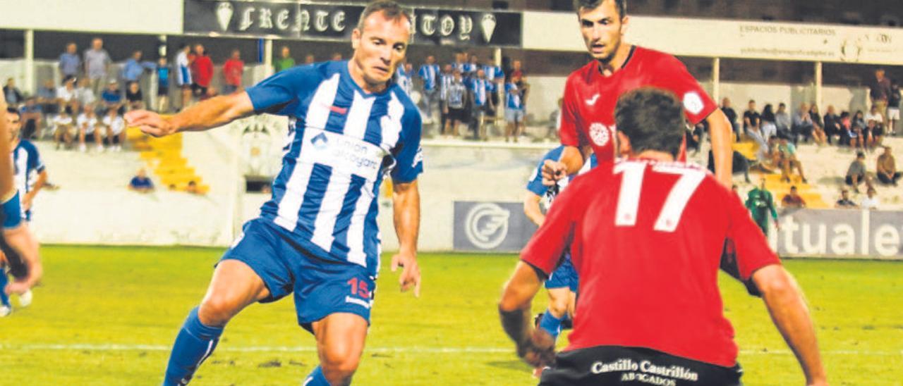 Juli, que volvía al Alcoyano, controla el balón ante dos jugadores del Saguntino.