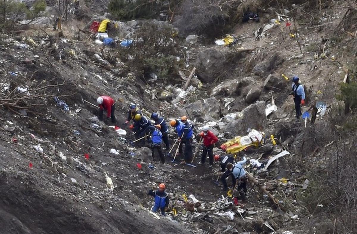 Gendarmes i investigadors, entre les restes de l’avió estavellat als Alps.