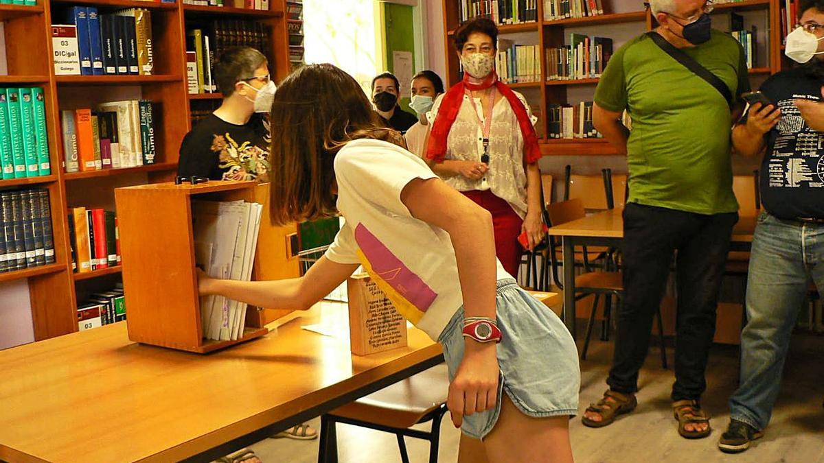 Una alumna introduce su recuerdo en la cápsula del tiempo en el instituto María Soliño.   | // FDV