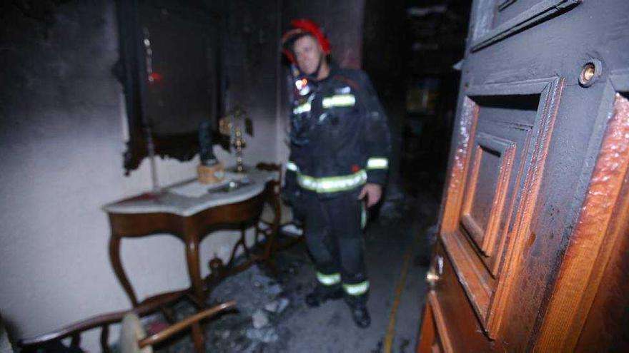 Un bombero examina los efectos de un incendio en una vivienda.