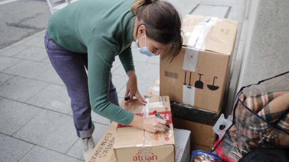 Arriba, voluntarios en la tienda “Marta Bonet” organizando la recogida. Abajo, Yulia etiquetando las cajas en ucraniano.  | FOTOS: PABLO HERNÁNDEZ 